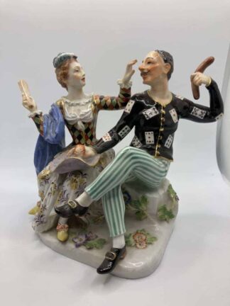 A Harlequin seated facing Columbine in playful / slapstick pose