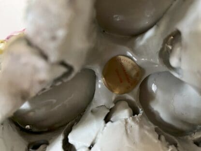 close up of the underside of the shell centrepiece, highlighting the previous dealer label and some of the original firing cracks